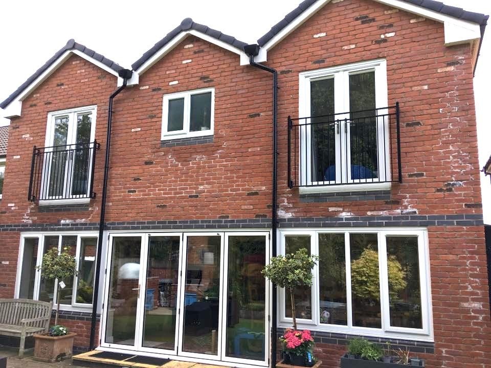 The rear of a brick house with new bifold doors and two Juliet balconies