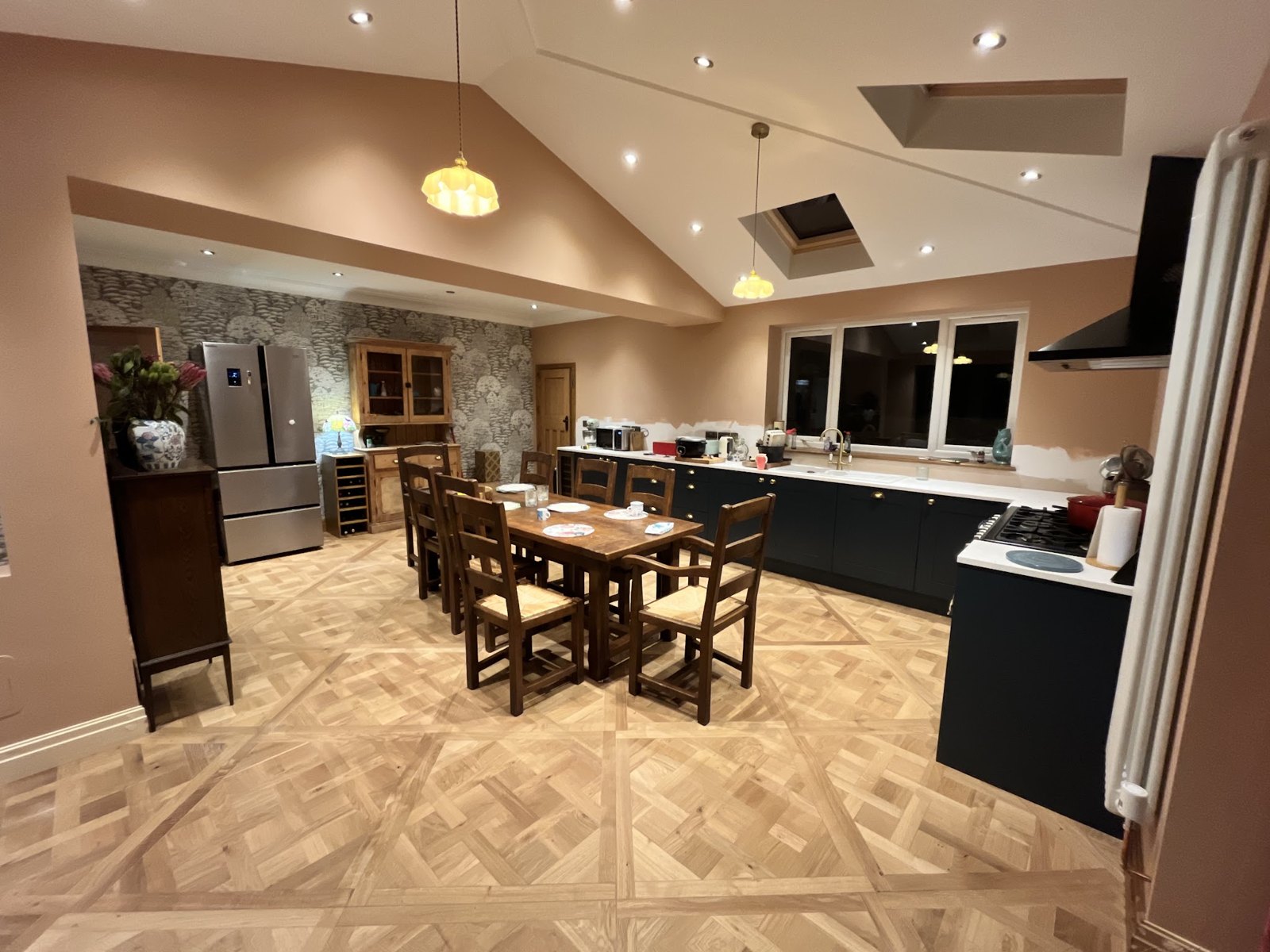 The finished kitchen and dining room, with a vaulted ceiling, rooflights and a patterned wood floor