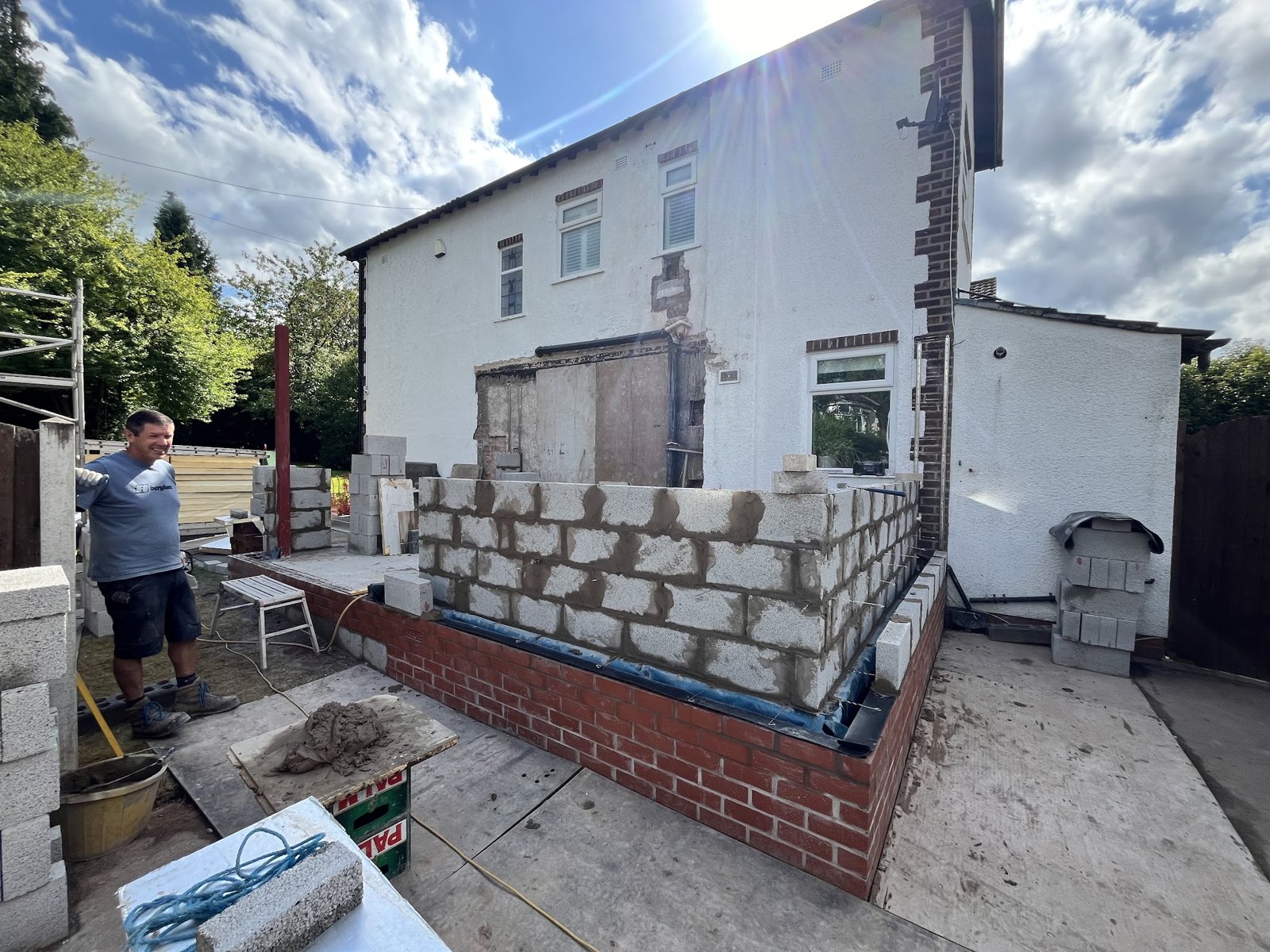 The first courses of blockwork for an extension at the back of a white house