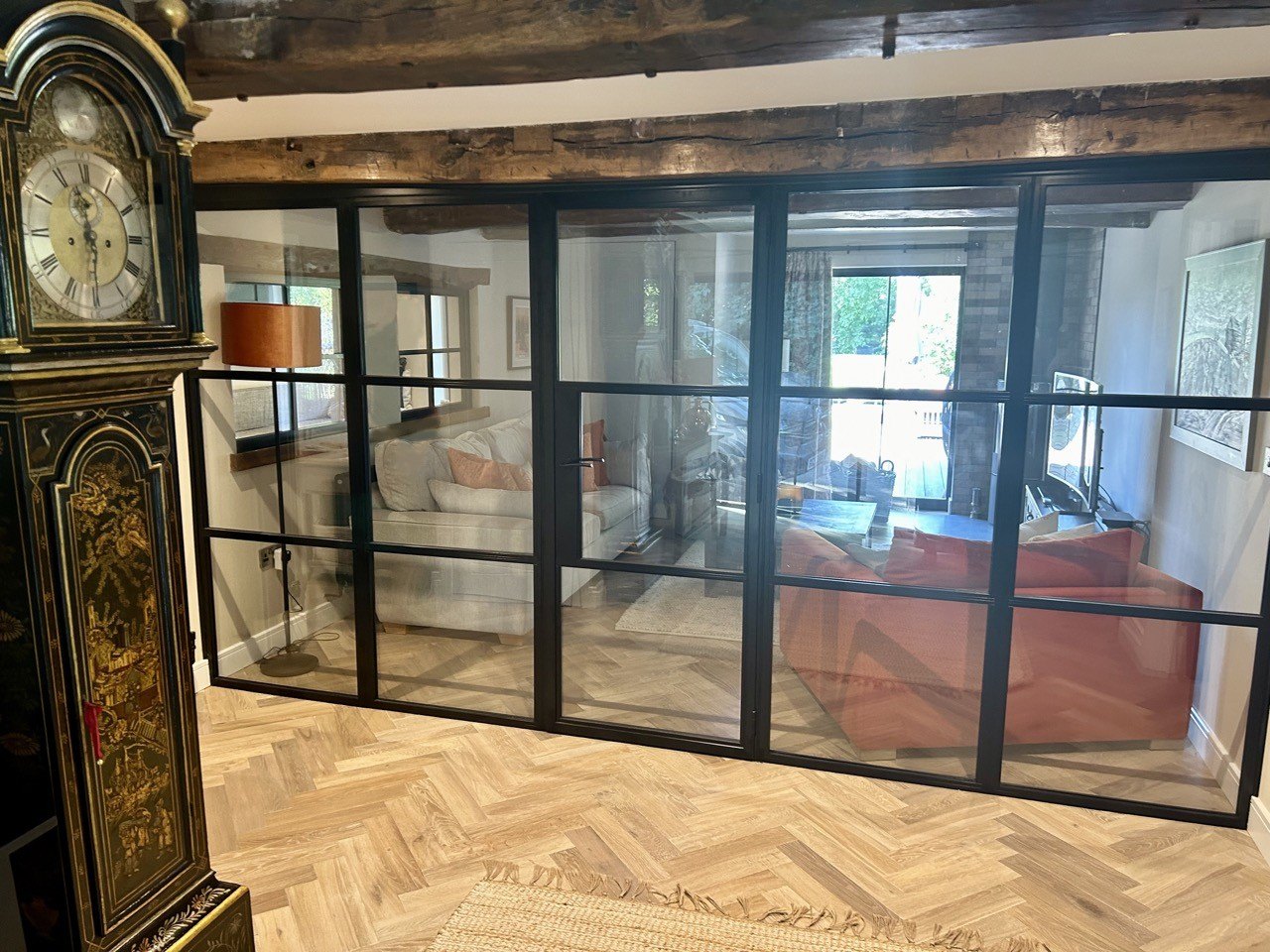 A hall with black steel-framed glazed doors and a herringbone floor